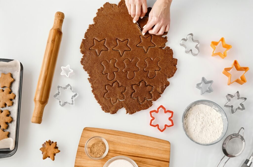 pexels-photo-6061742-6061742 Top view of gingerbread dough with cookie cutters, flour, and rolling pin, ideal for festive baking themes.